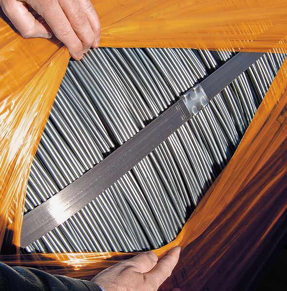 Steel rods completely wrapped in BioCor® corrosion protection film. Two overlapping layers of film are pulled apart by one person, revealing the steel rods.